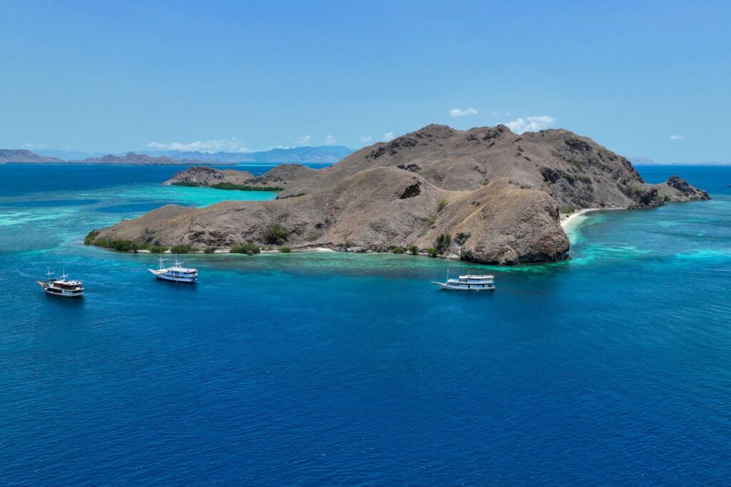 Liveaboard boats anchored beside an island in Komodo National Park.