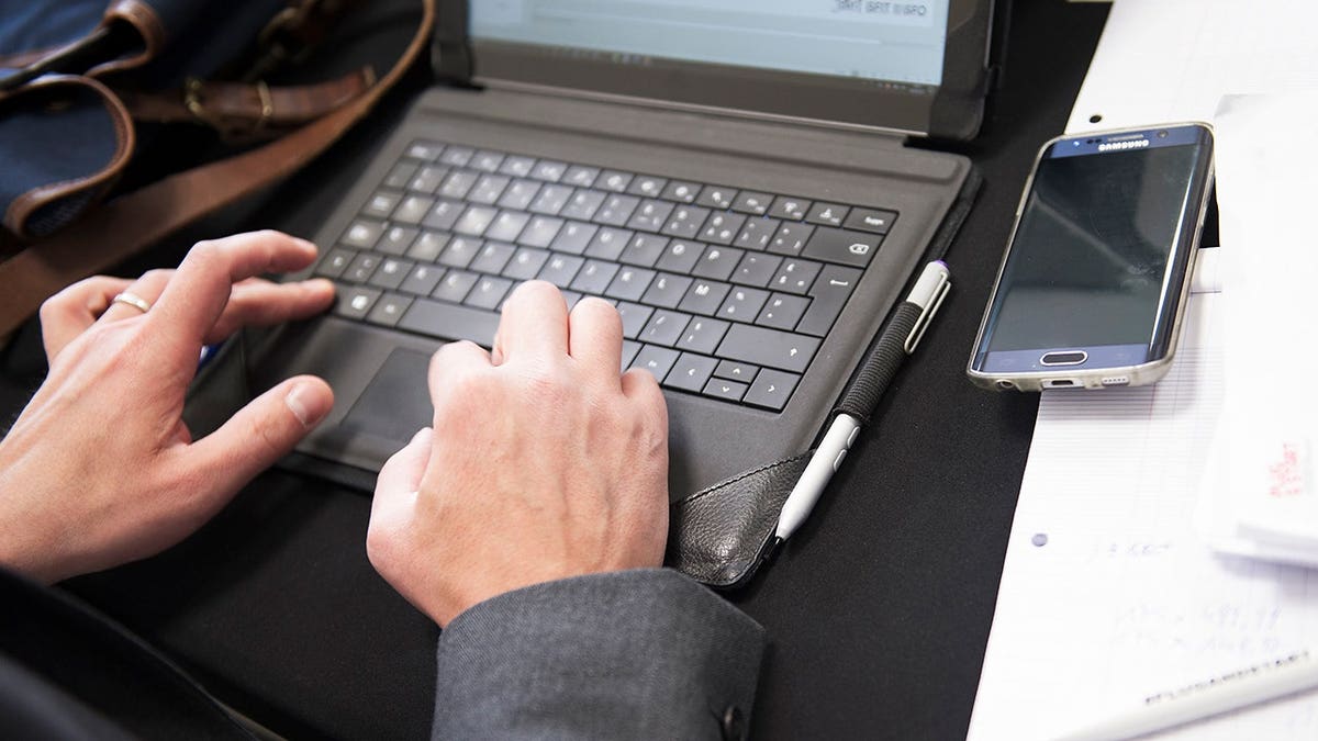 Man in a suit typing on his laptop.