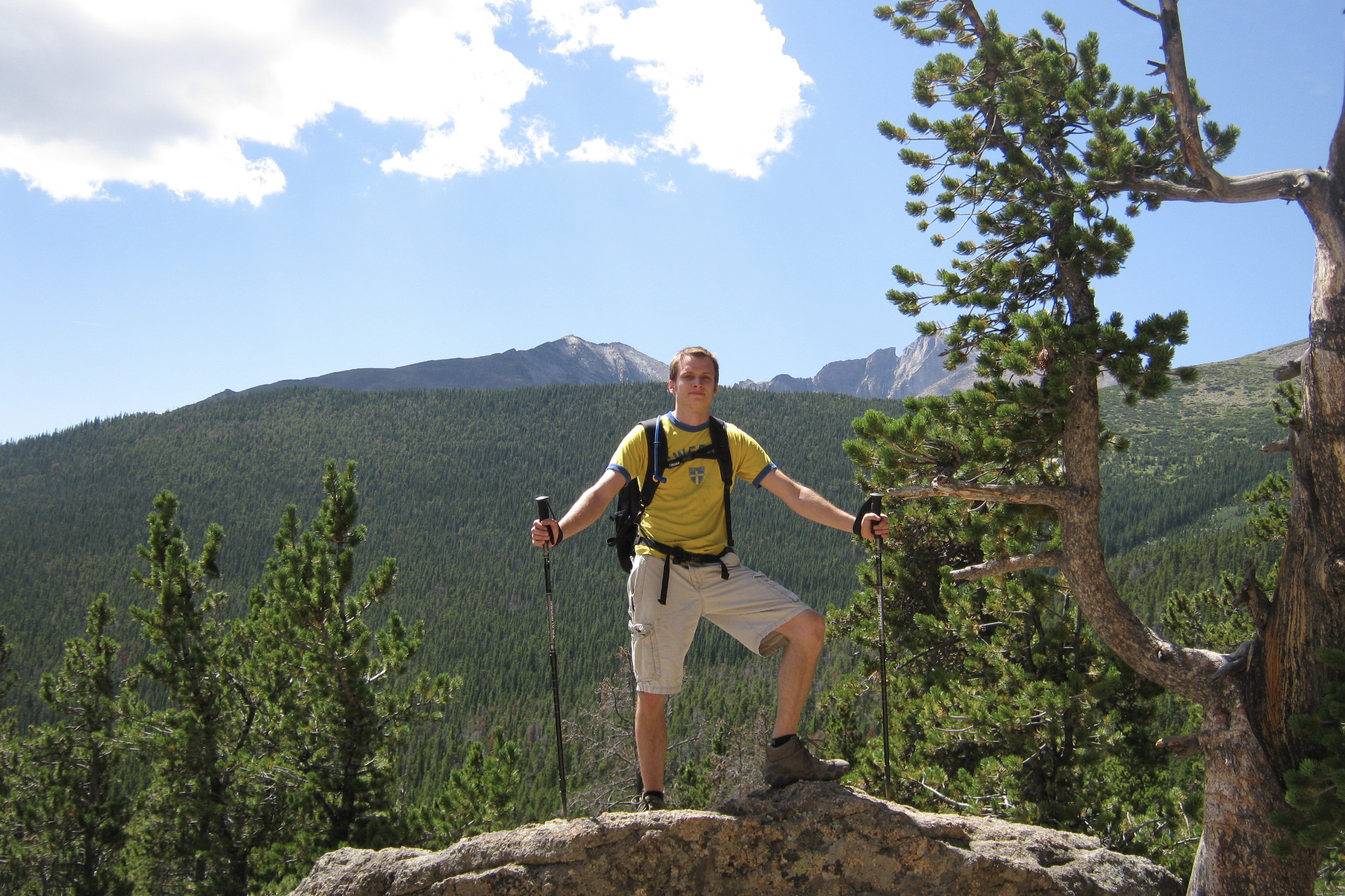 A photo of a young man with two hiking poles standing outside on the Appalachian Trail.