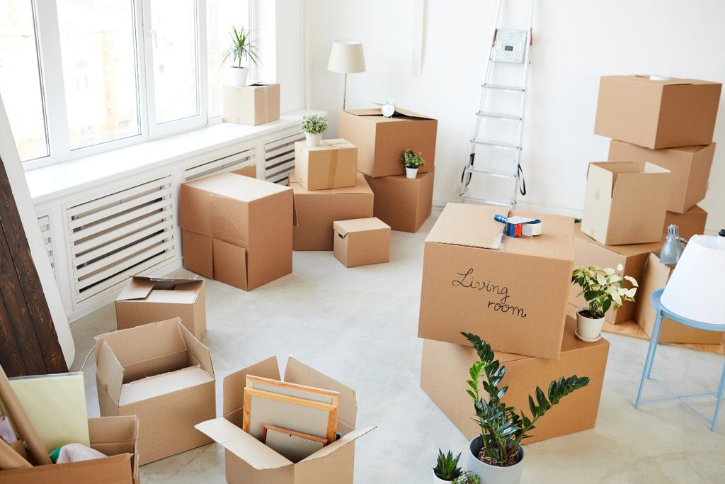 Cardboard moving boxes packed inside a bright living room.
