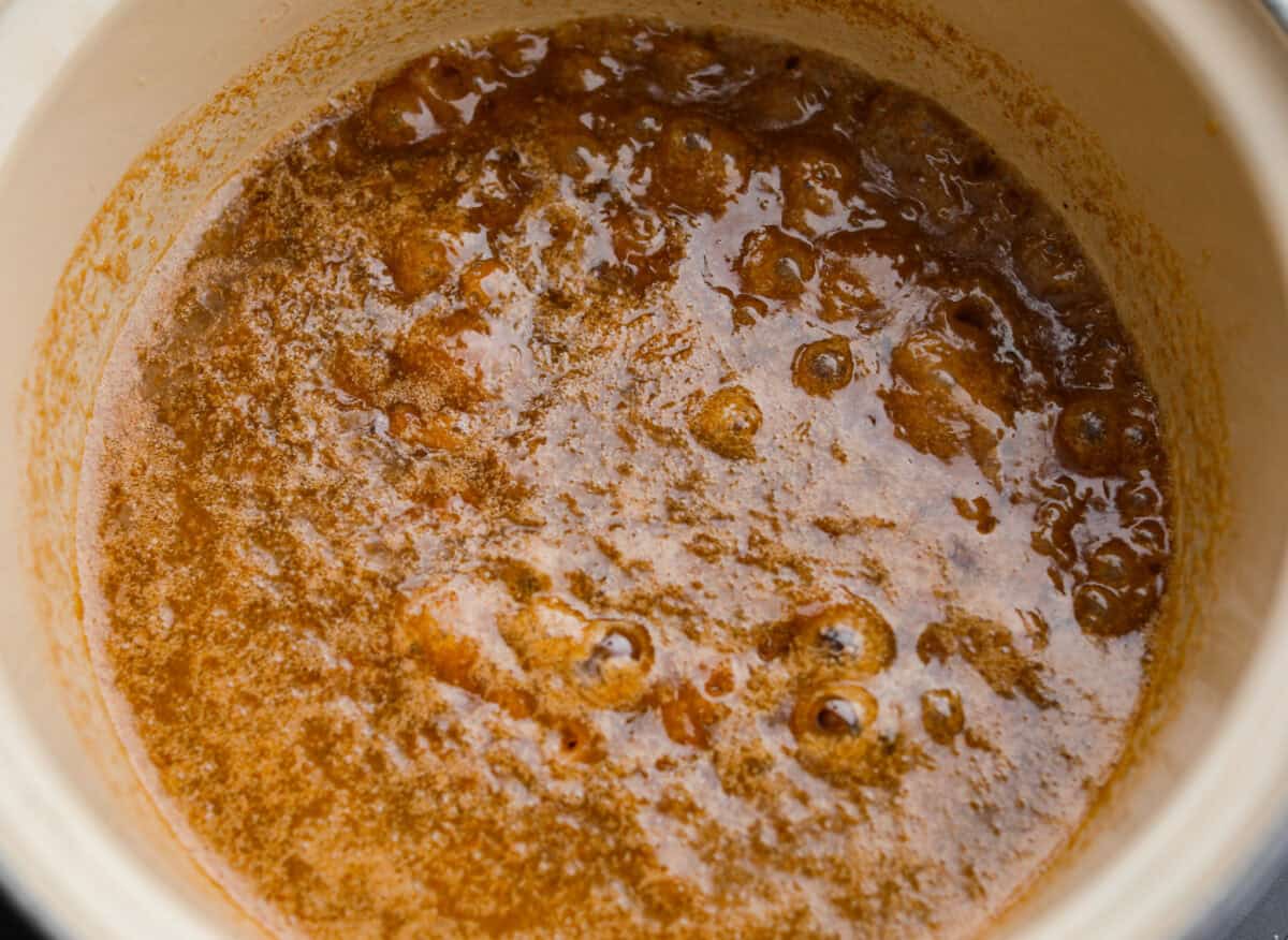 Pumpkin spice crack is Christmas crack with a fall twist! Buttery toffee, salty crackers, white chocolate, pumpkin pie spice, and crunchy praline pecans make this an easy treat you won’t be able to stop snacking on. Toffee cooking in a pot.