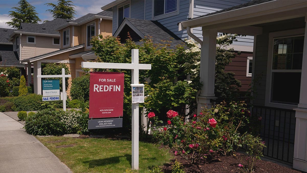 For sale signs sit outside houses.