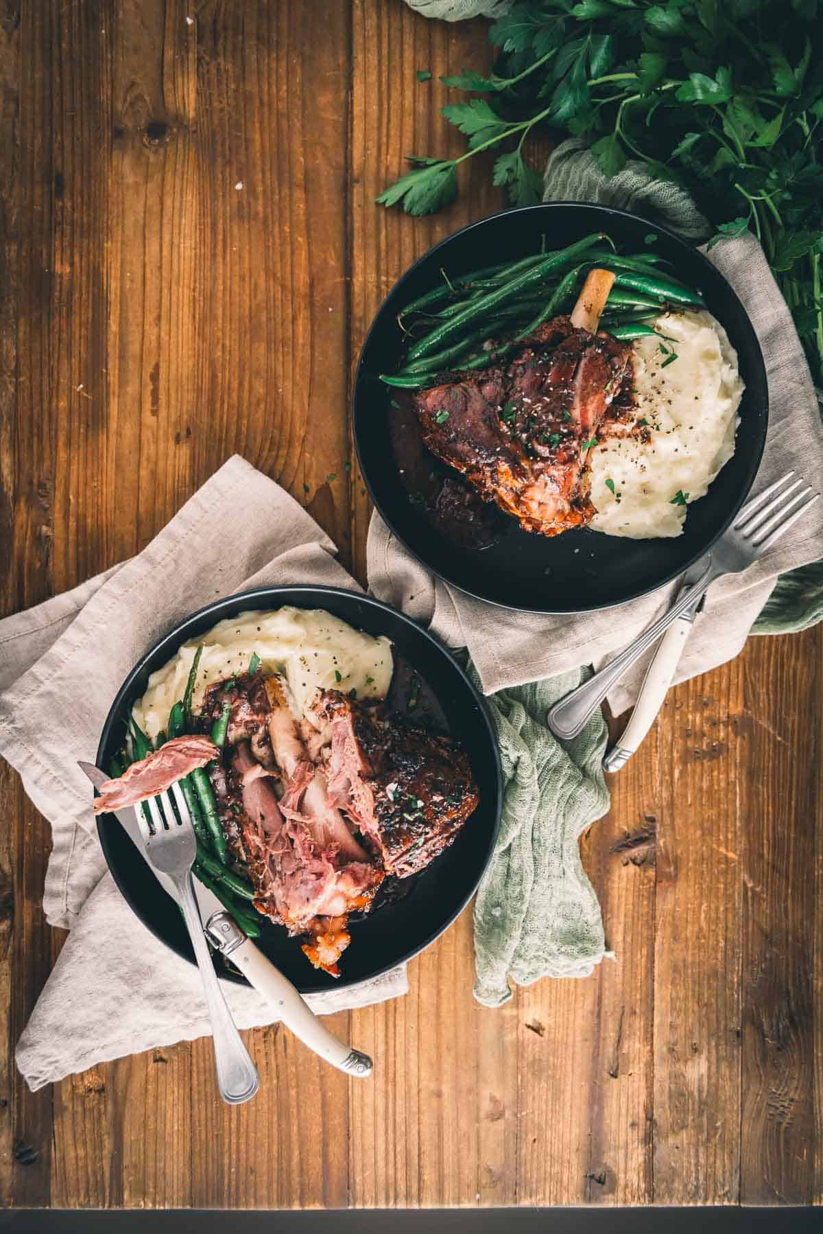 Sous vide lamb with mashed potatoes and green beans on a wooden table.
