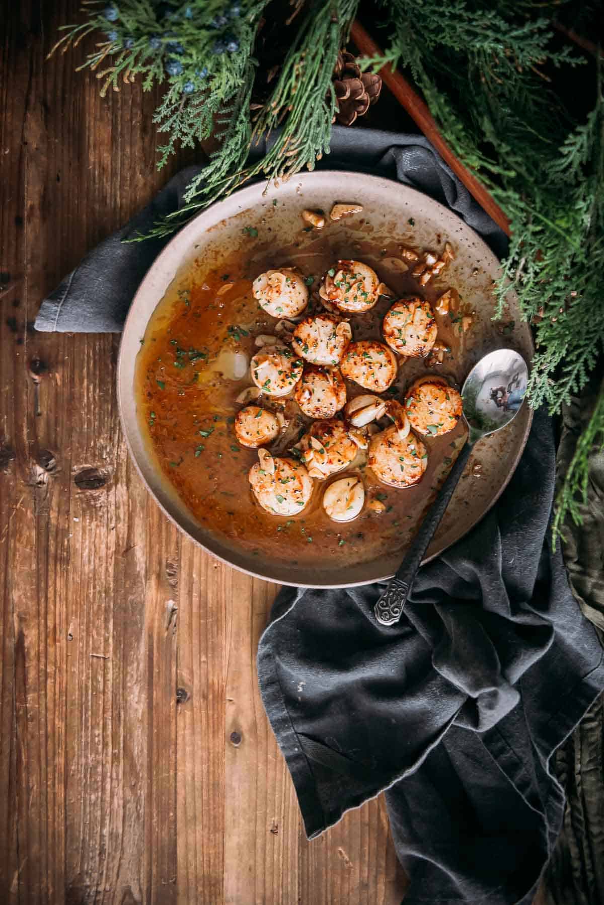 Platter of golden brown scallops on a wooden table.