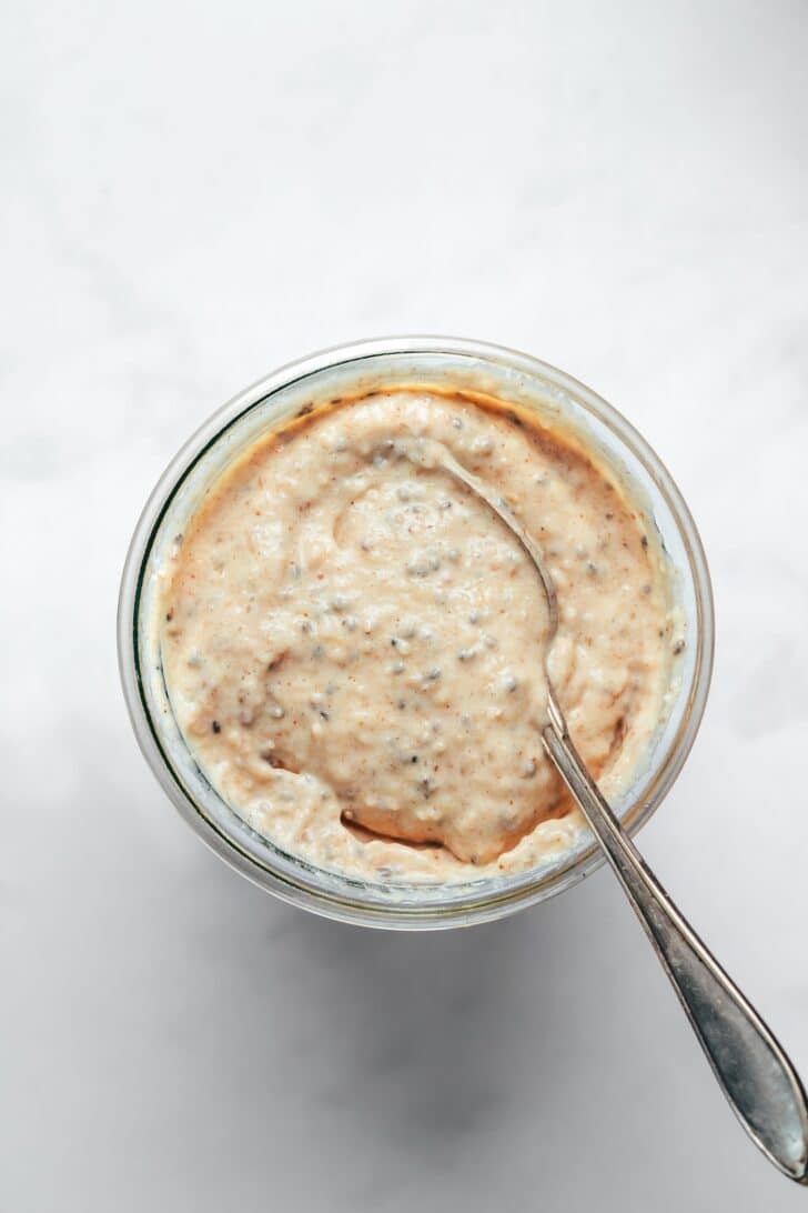 Creamy blended oats being spooned in glass jar