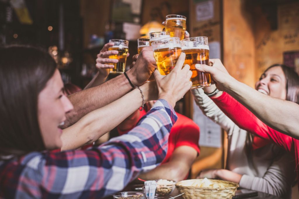 A group of young people raise their glasses in a bar