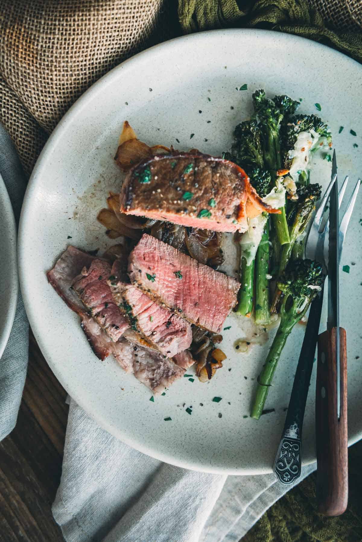 Overhead shot of a medium-rare filet sliced on a white plate.