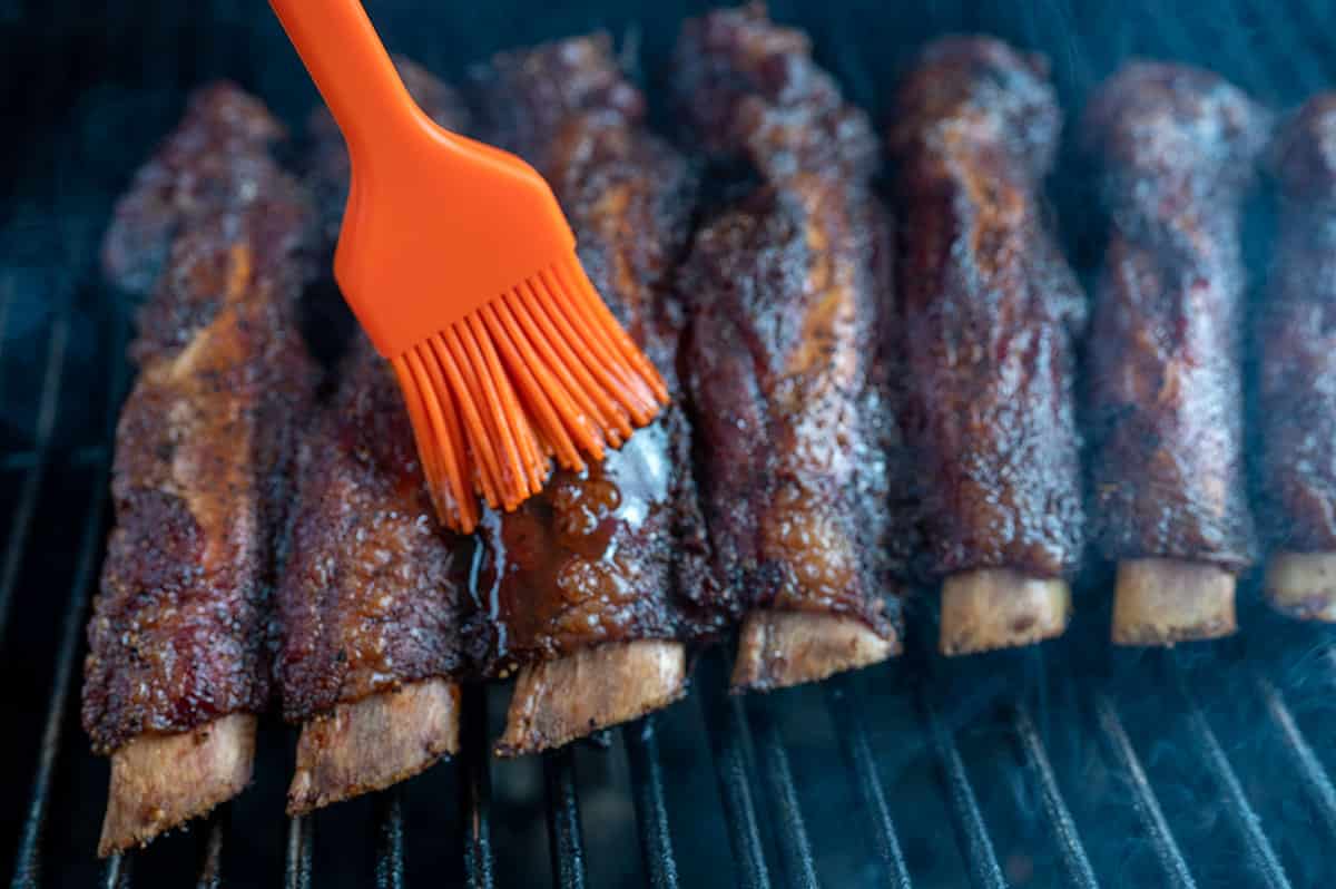 basting cola BBQ sauce on beef back ribs.