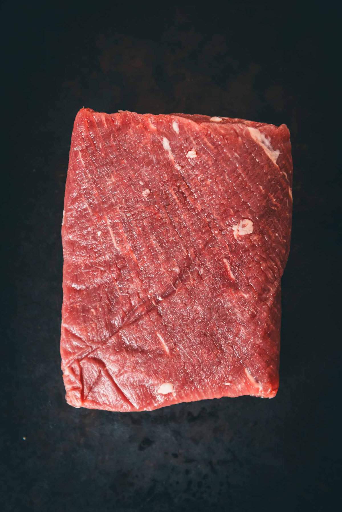 Raw blade steak on black board.