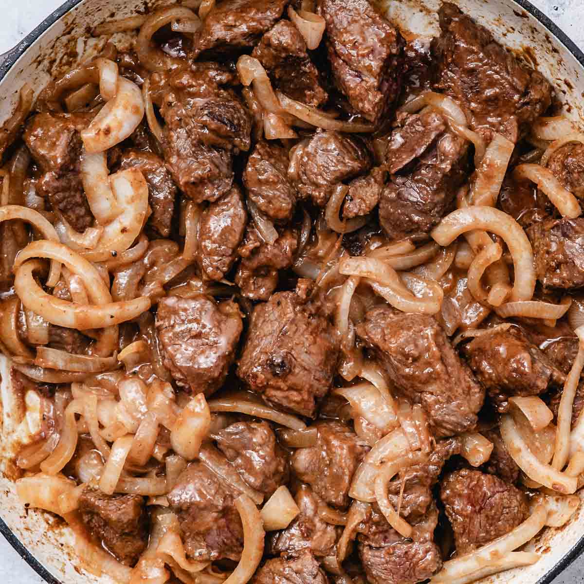 Browned beef and sliced onions cooking in a pot