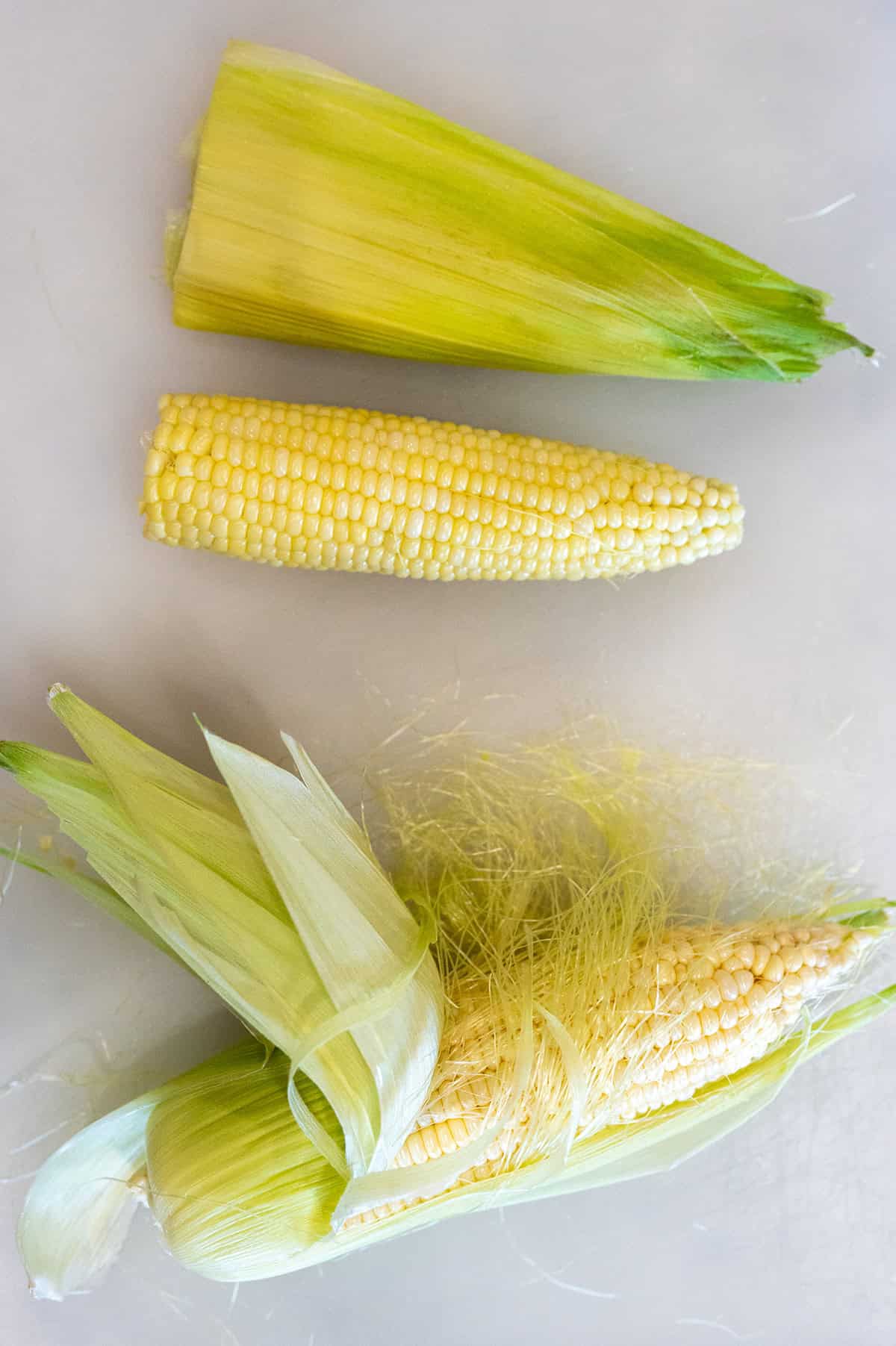 two ears of corn with husk removed.