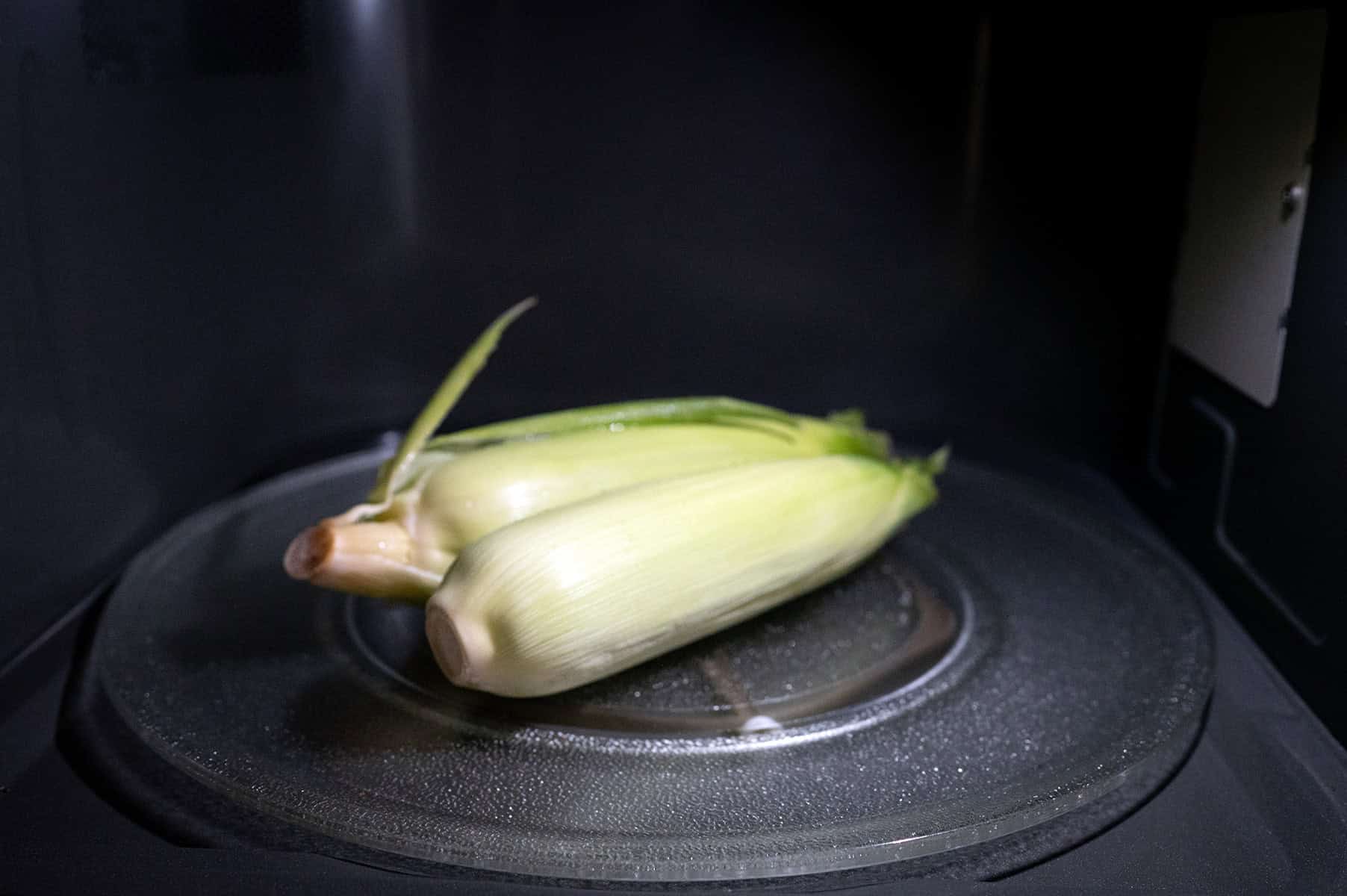 Two ears of corn in the microwave.