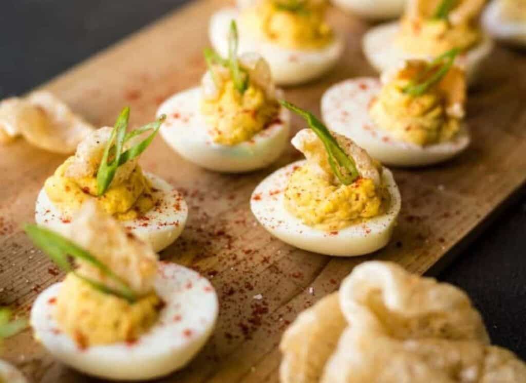Deviled eggs on a platter with crispy fried pork skin on top.