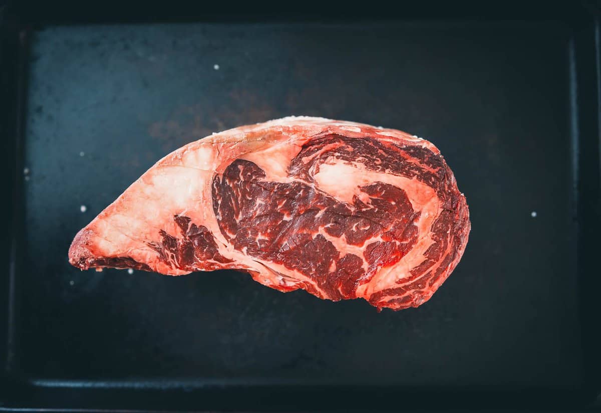 A USDA choice boneless rib roast showing the different muscles, fat cap and marbling.