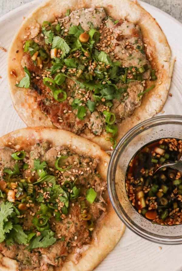 smash dumpling tacos on a white plate with dipping sauce