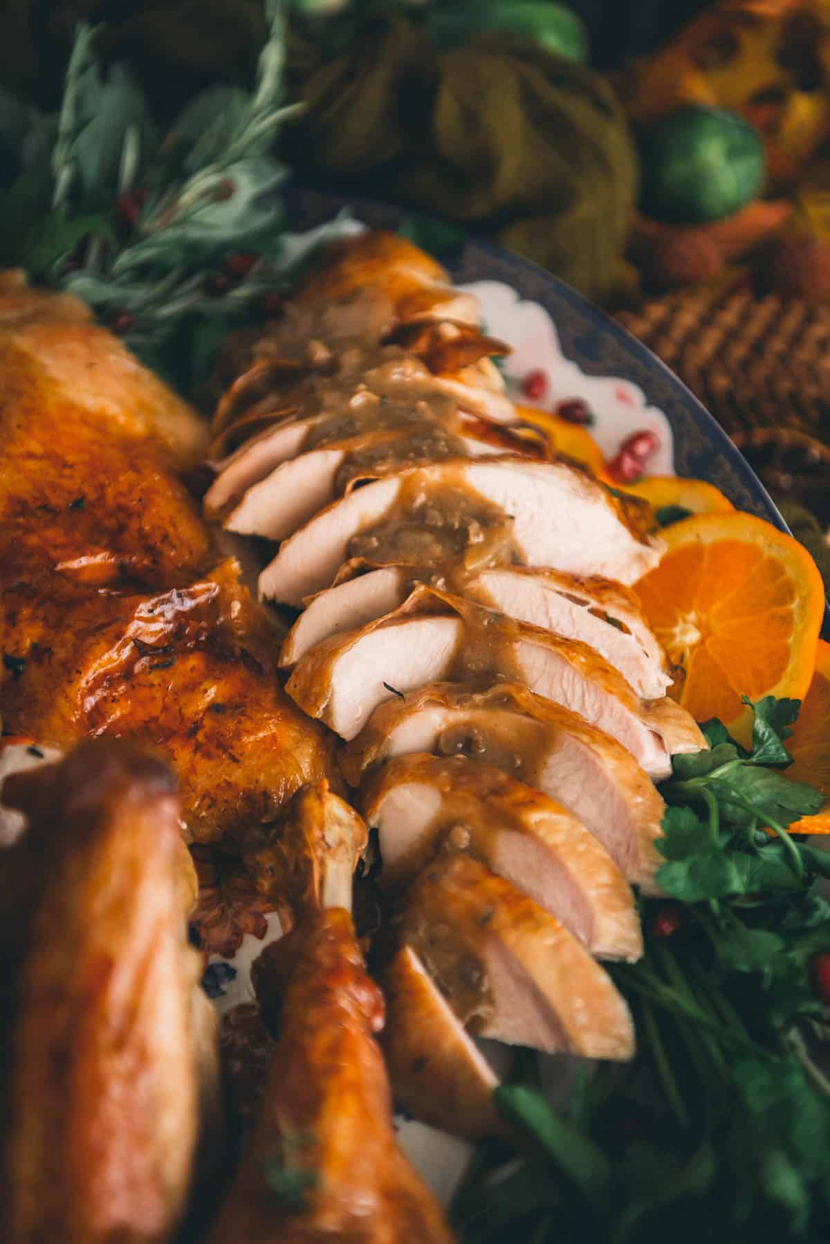 Sliced turkey breast, drizzled with giblet gravy on a serving platter.