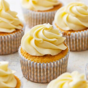 frosted gluten-free vanilla cupcakes in cupcake liners.