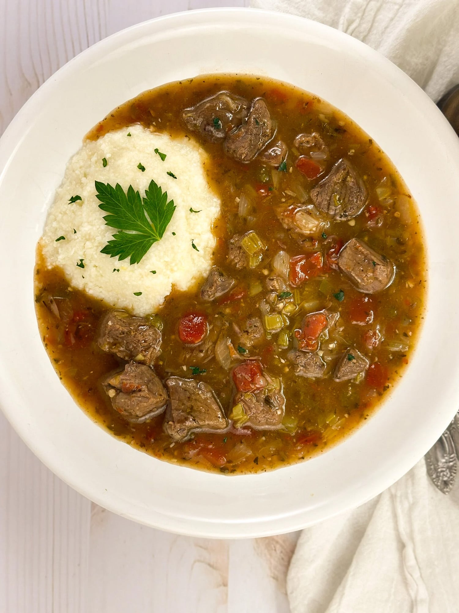 Grillades and grits closeup in round white bowl.