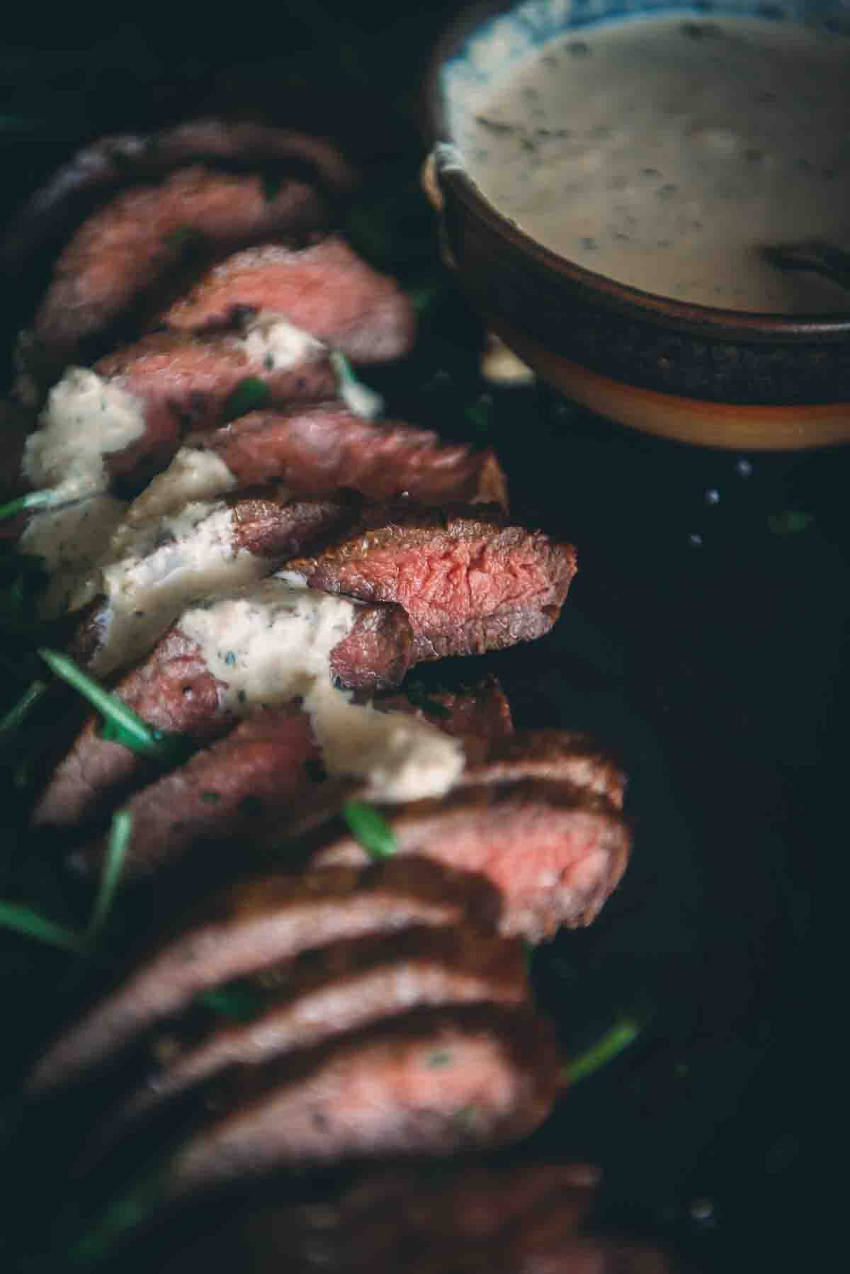 A plate of steak with a sauce on it.