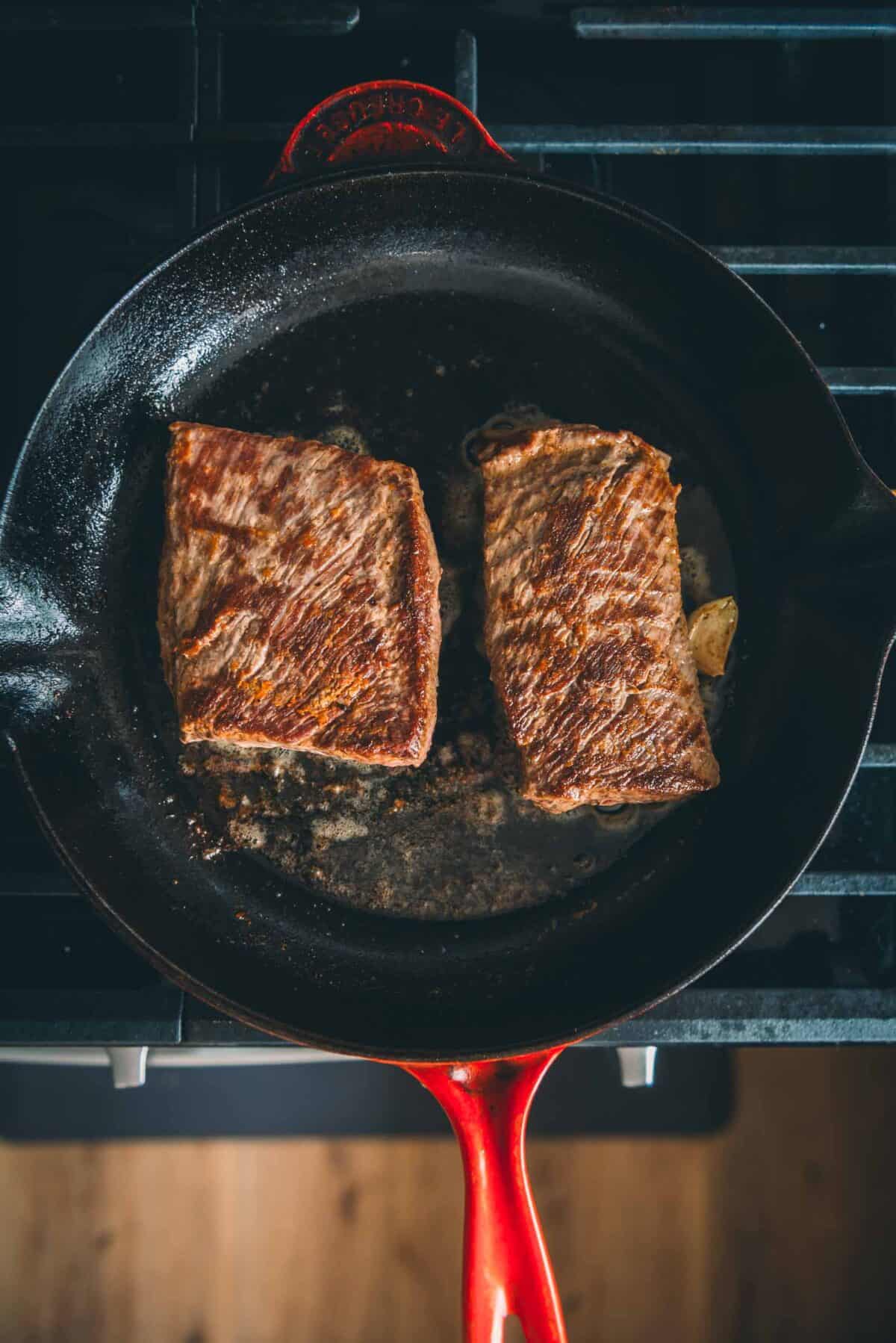 Steaks seared and flipped in the pan to finish cooking.