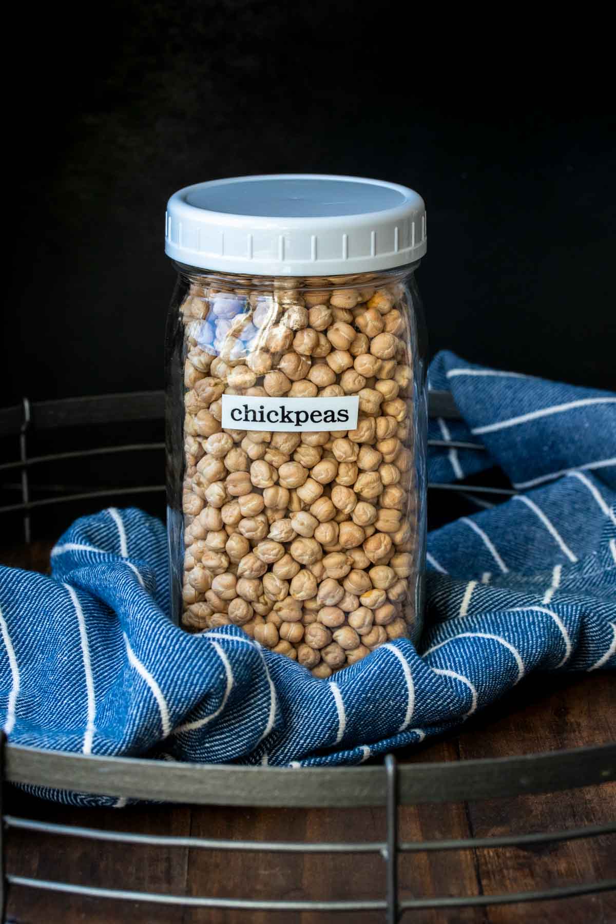 Are you ready to learn how to use pantry staples in your meals? This guide on how to cook dried chickpeas is exactly what you need to get your started! #pantrystaples #cookingbasics Glass jar with white plastic lid filled with dried chickpeas