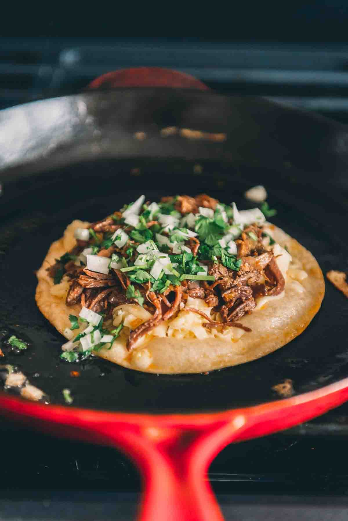 Showing the minced onion and cilantro over the beef as you build the quesadilla. 