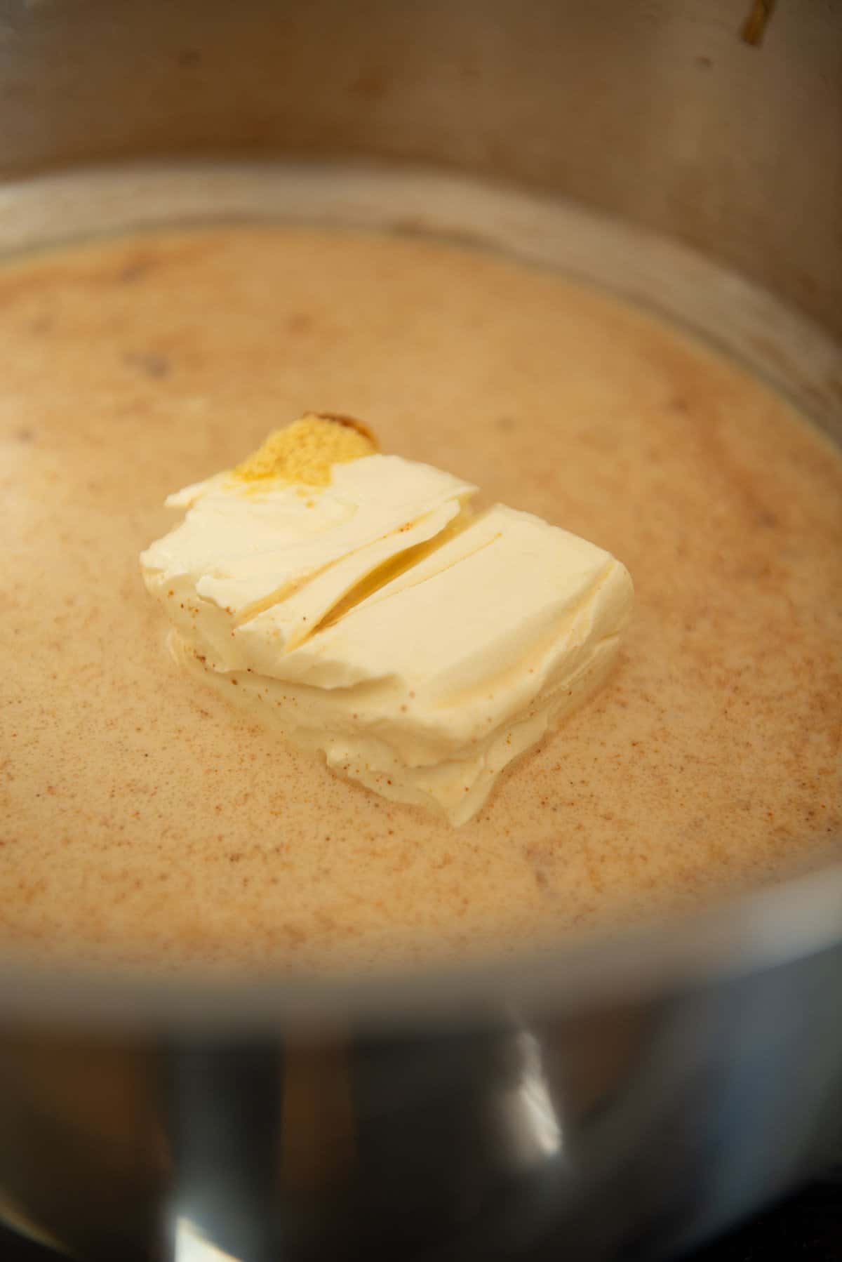 A piece of butter in a pot on a stove.