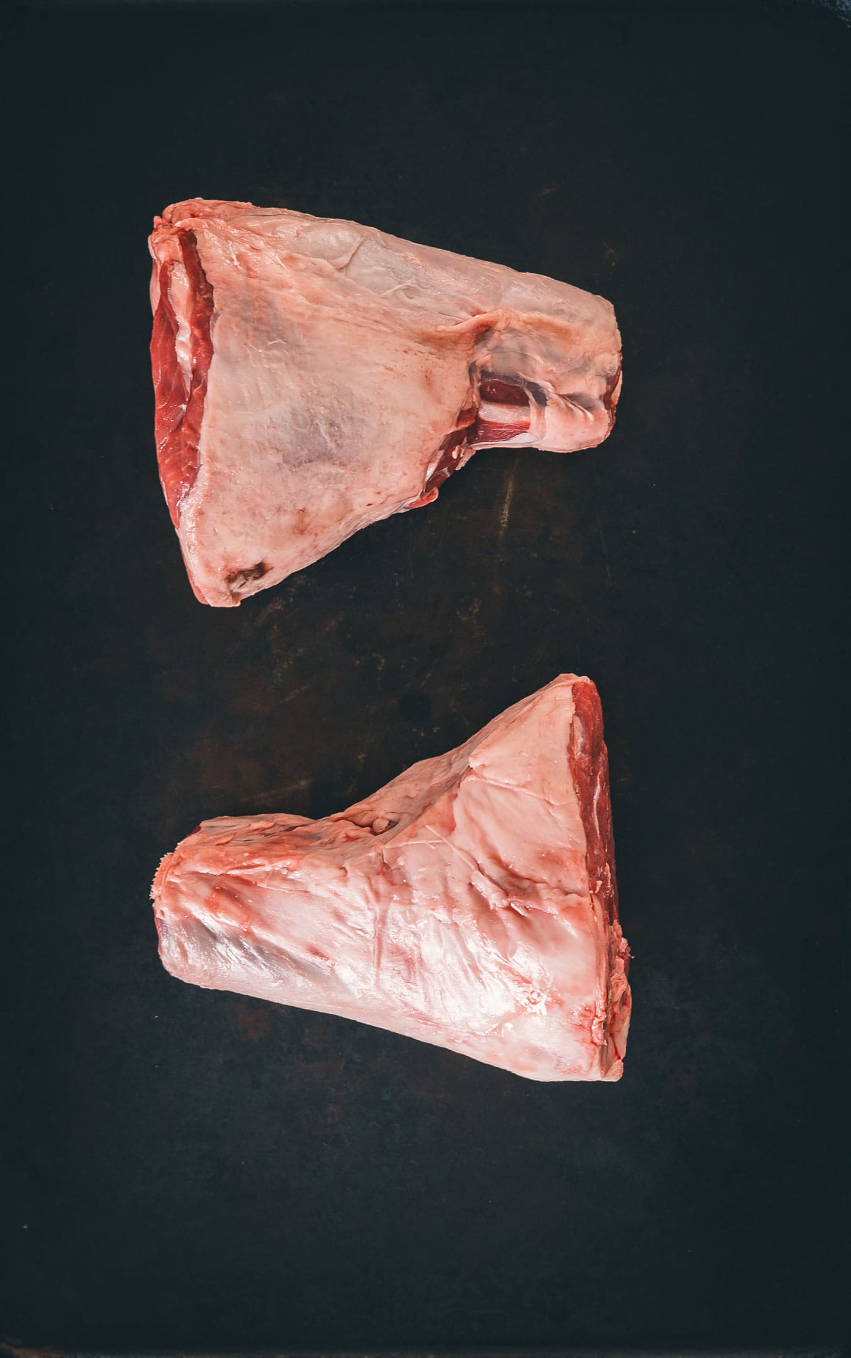 Two lamb shanks on a black background.