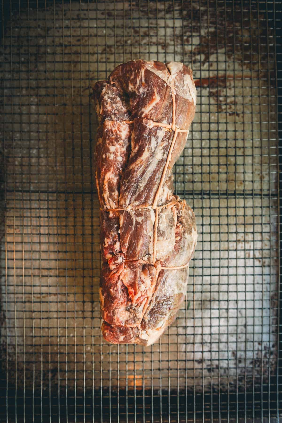 Raw beef tenderloin, showing the beef cut tied with kitchen twine.
