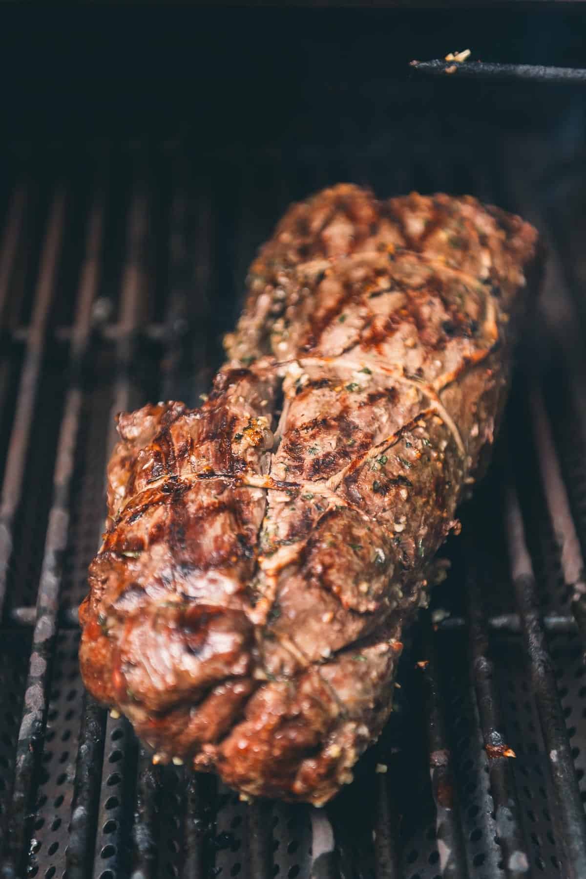 Grill marks searing the outside of the tenderloin roast as it finishes on the hot side of the grill.