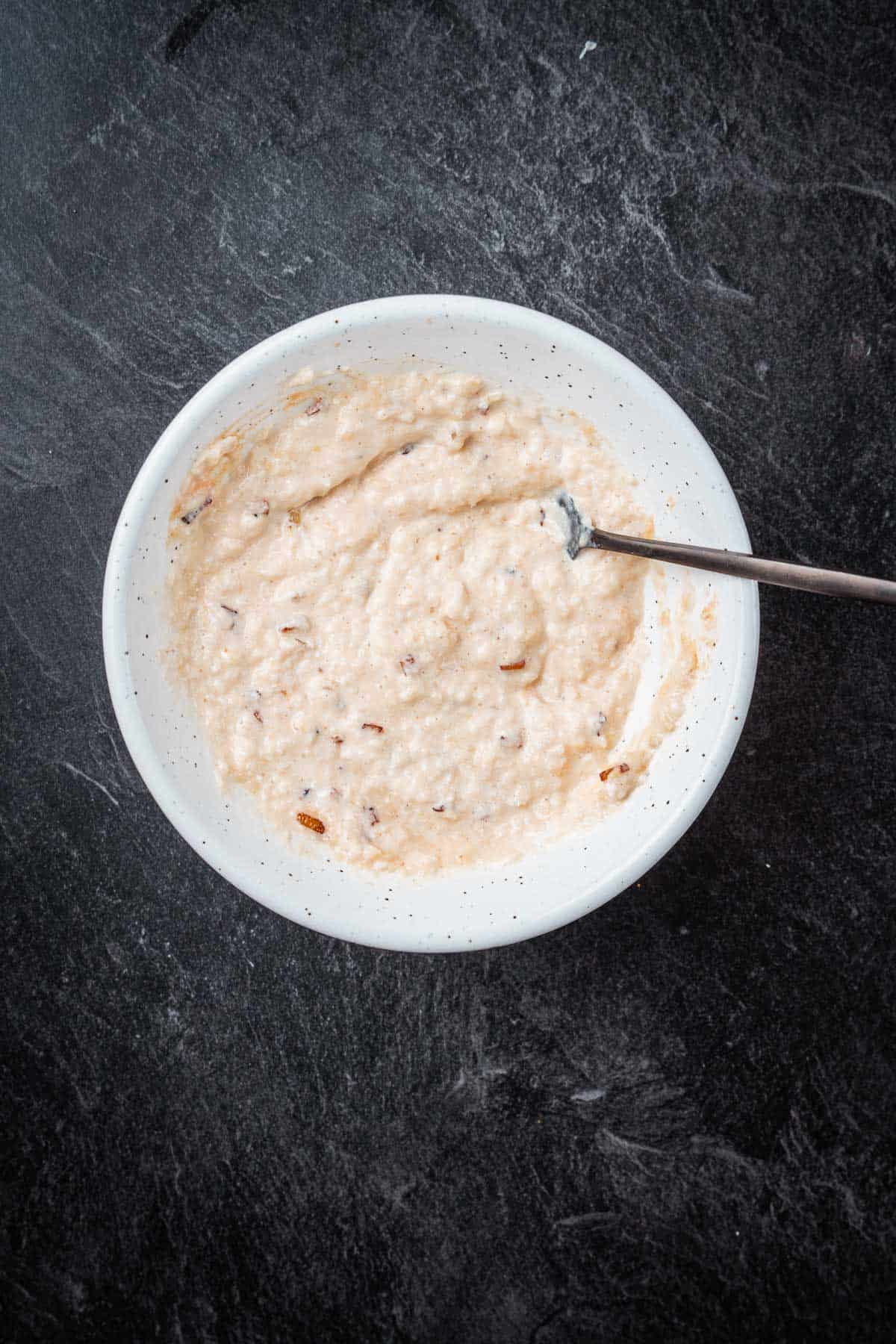 Oatmeal in a white bowl with a spoon.