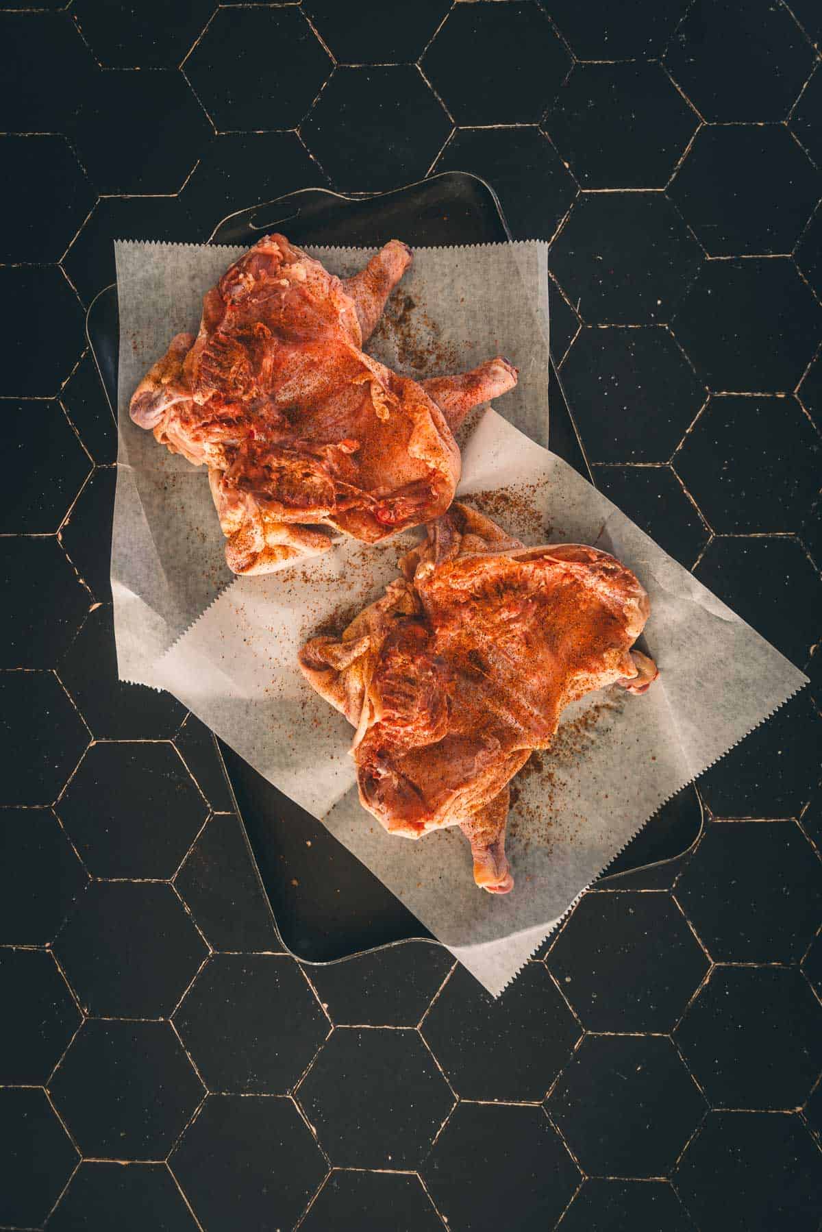 Spatchcocked hens flipped to season the inside of the birds.
