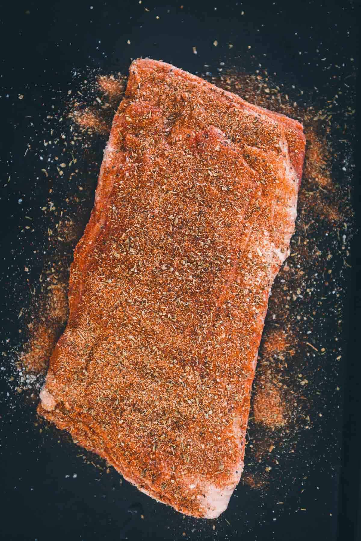 Lamb ribs dusted with spices on a baking sheet.