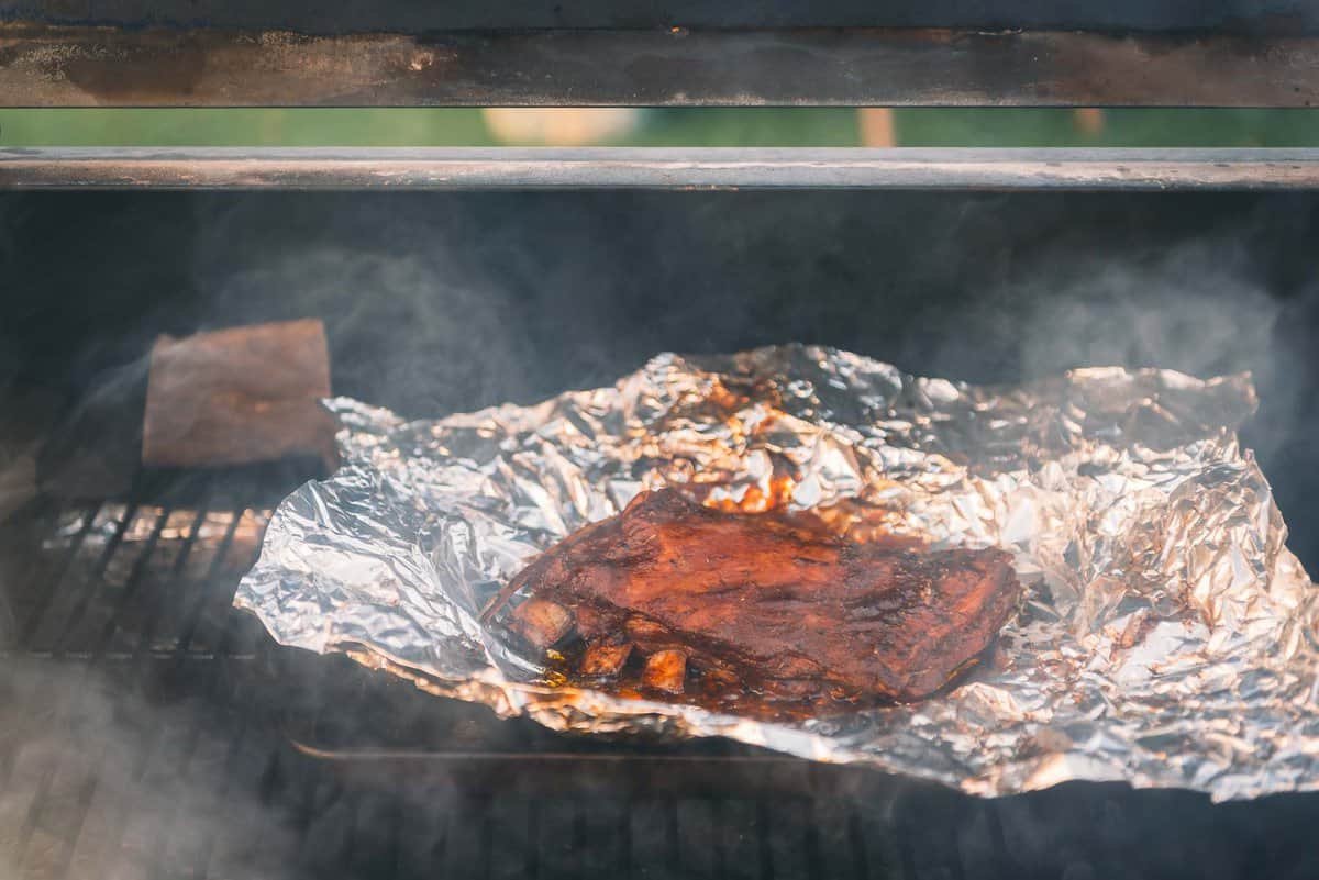 Lamb spare ribs being cooked on a grill.