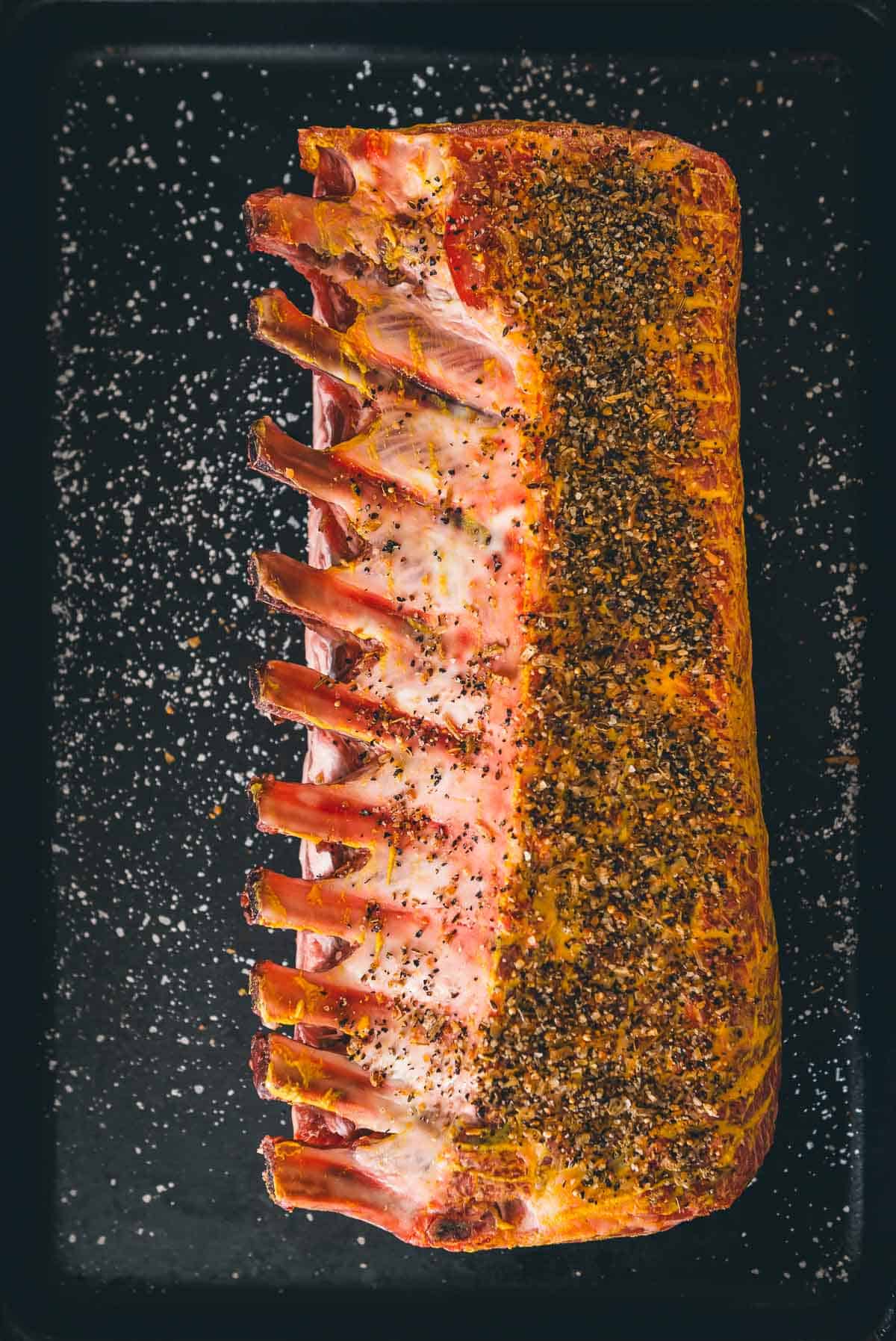 Pork roast, bone side up seasoned with spices.