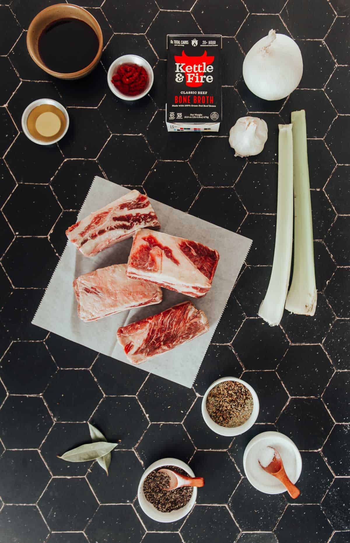 A table with ingredients on it for sous vide short ribs with a red wine reduction.