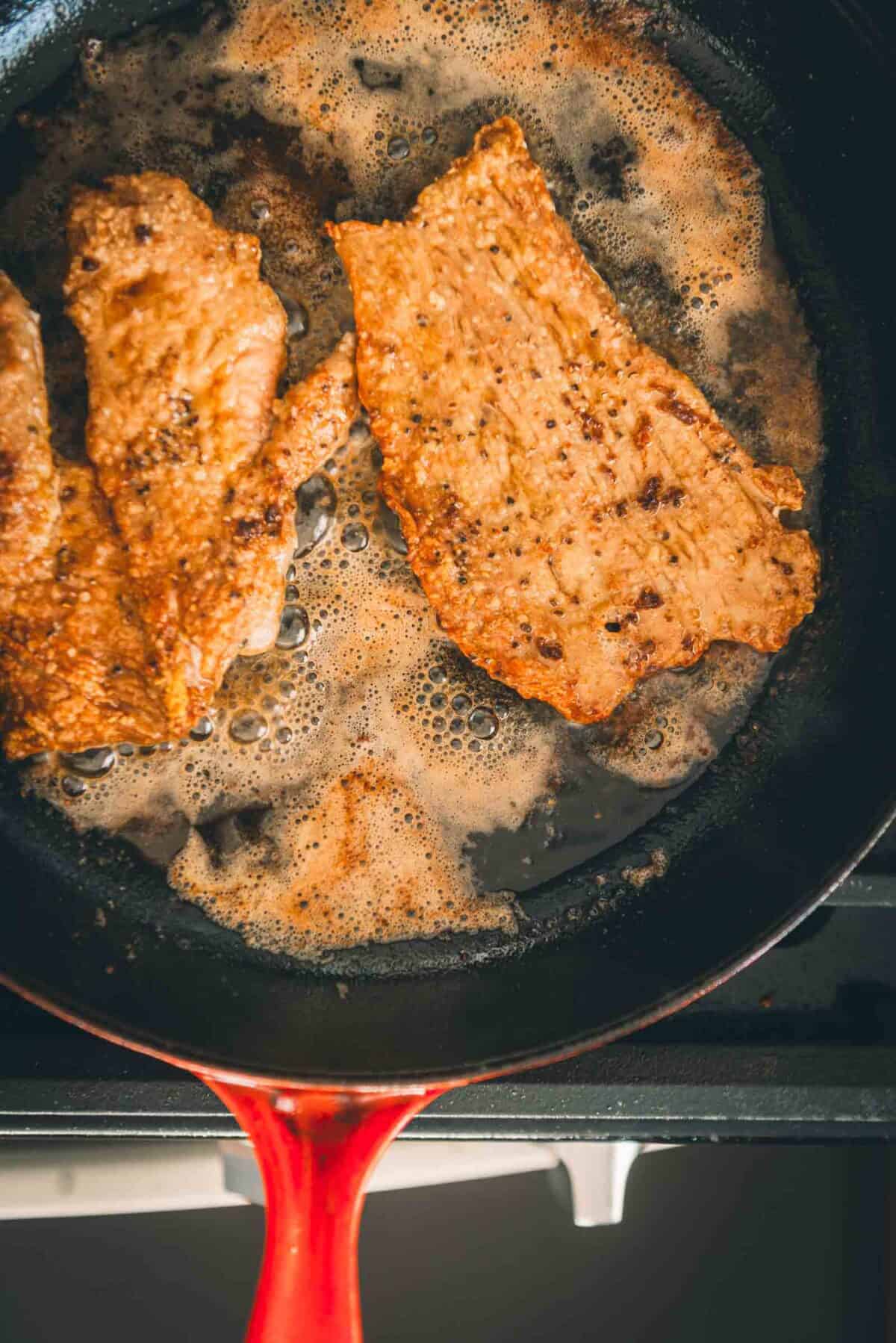 Fried veal in a frying pan on a stove.