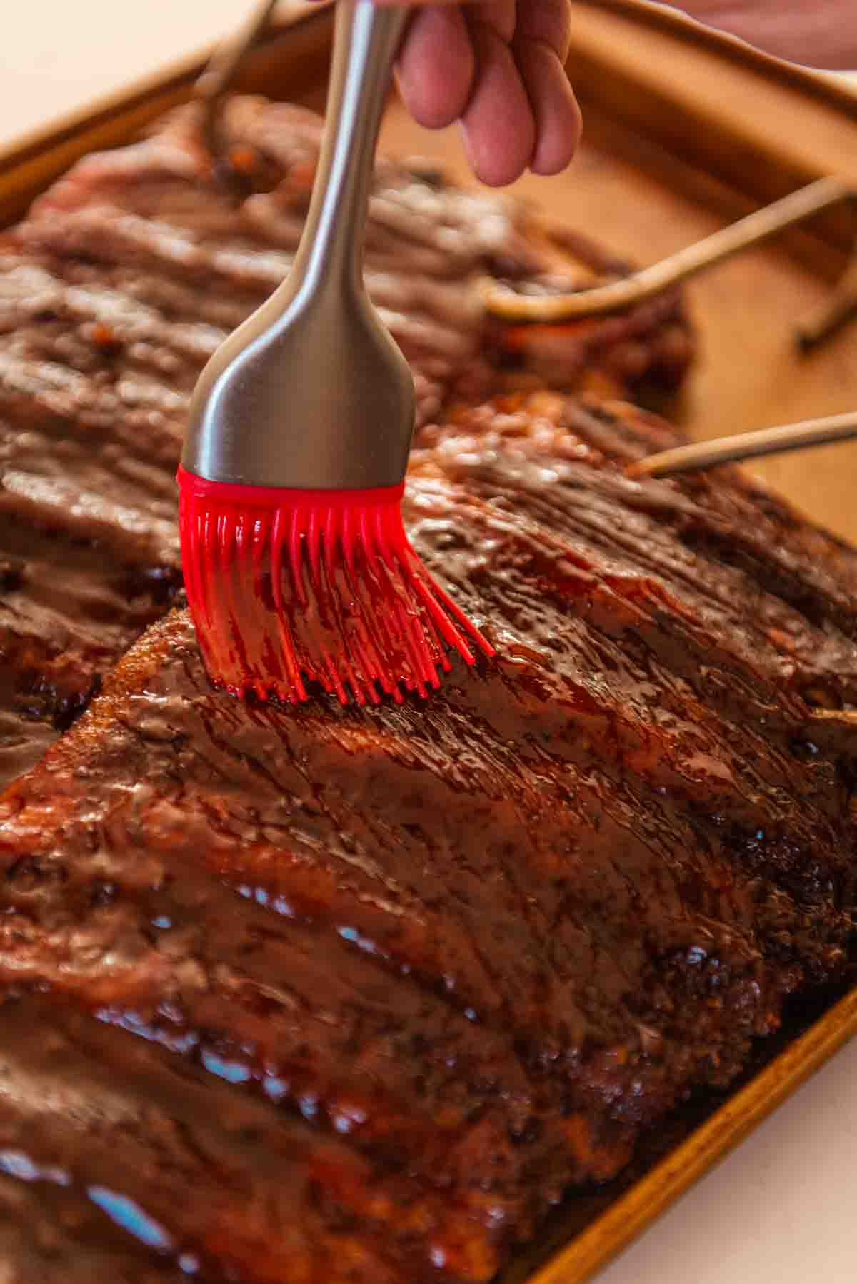 Basting the meat with bbq sauce. 