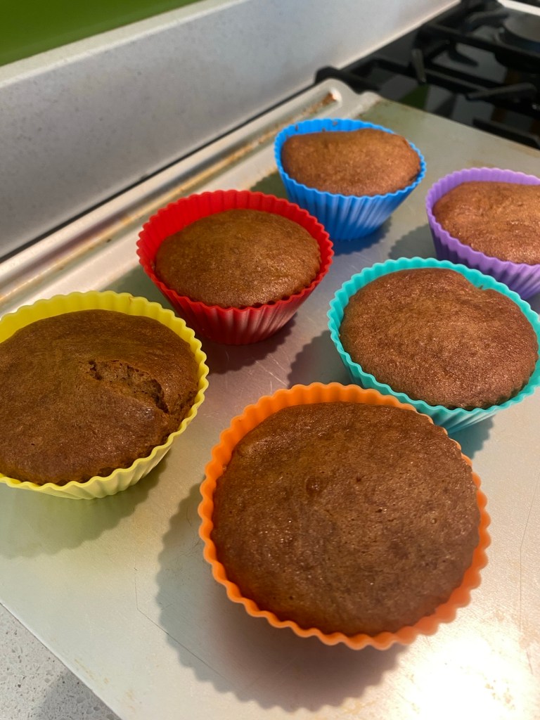 six coloured silicon cupcake cases containing freshly-baked coffee cupcakes