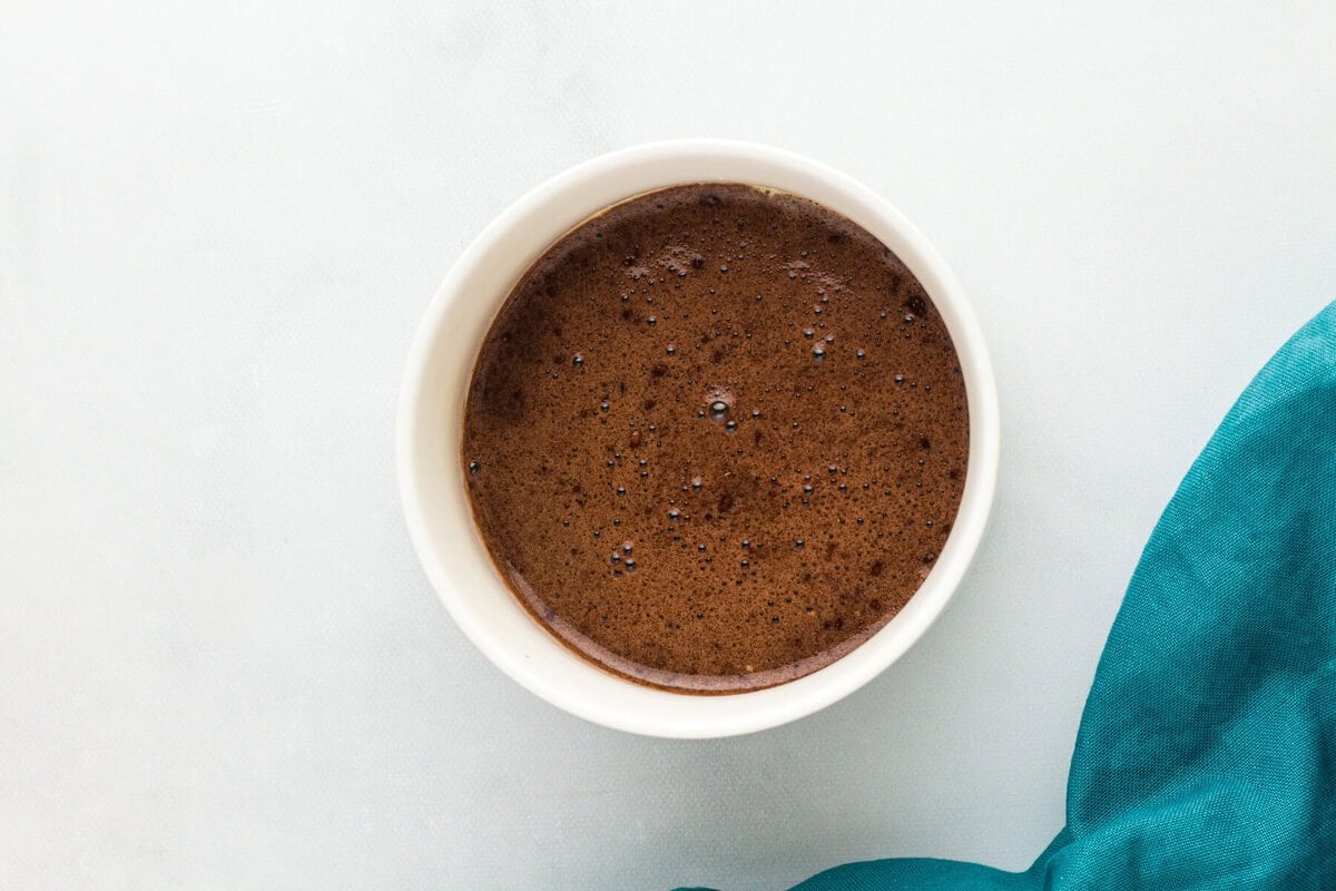 Overhead view of a flourless mug cake in a white ramekin, fresh out of the microwave