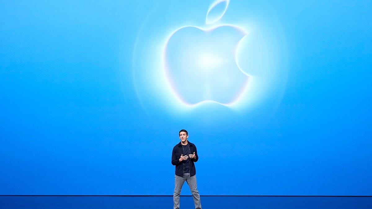John Ternus speaks in front of an Apple logo.