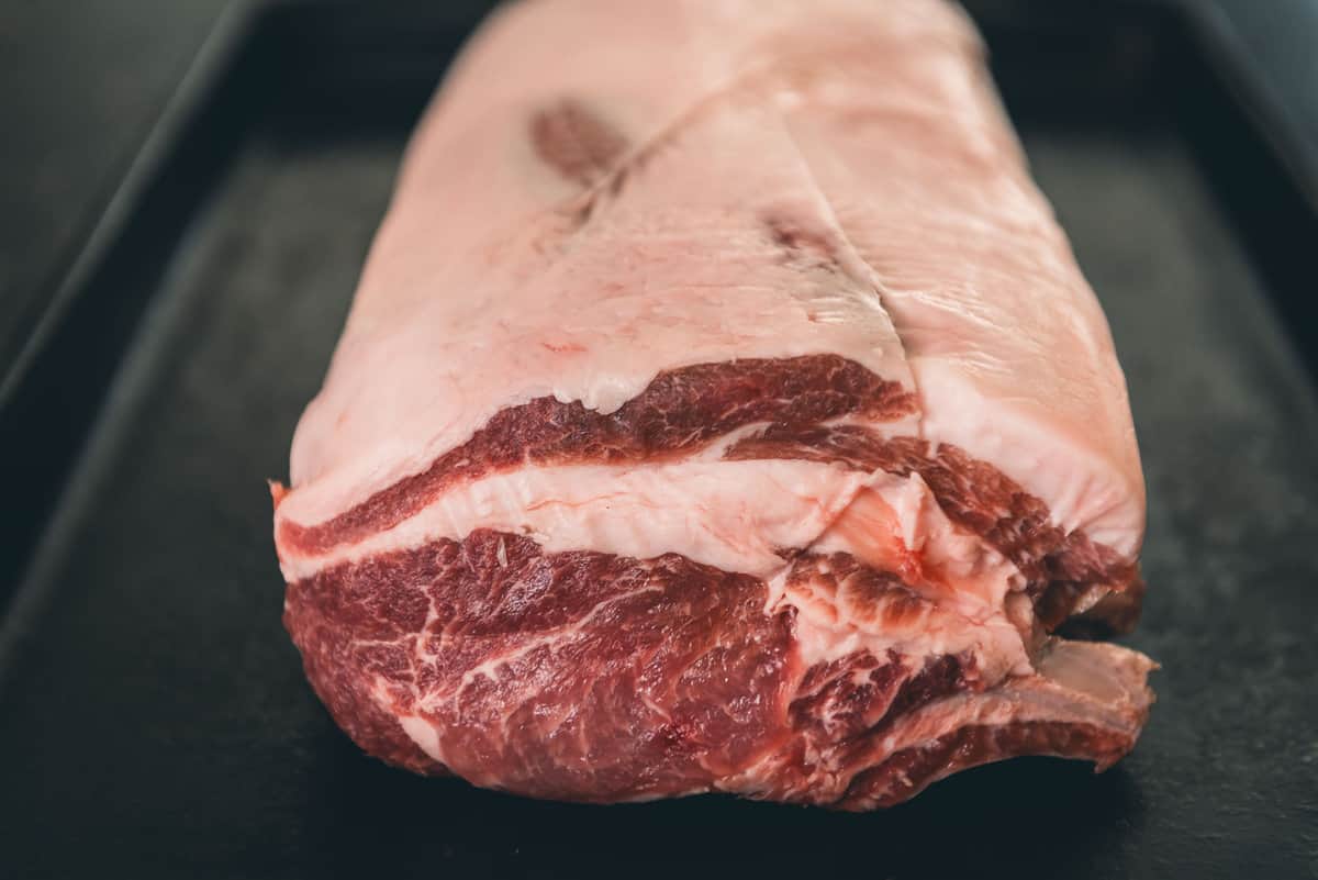 A rack of pork on a black tray.
