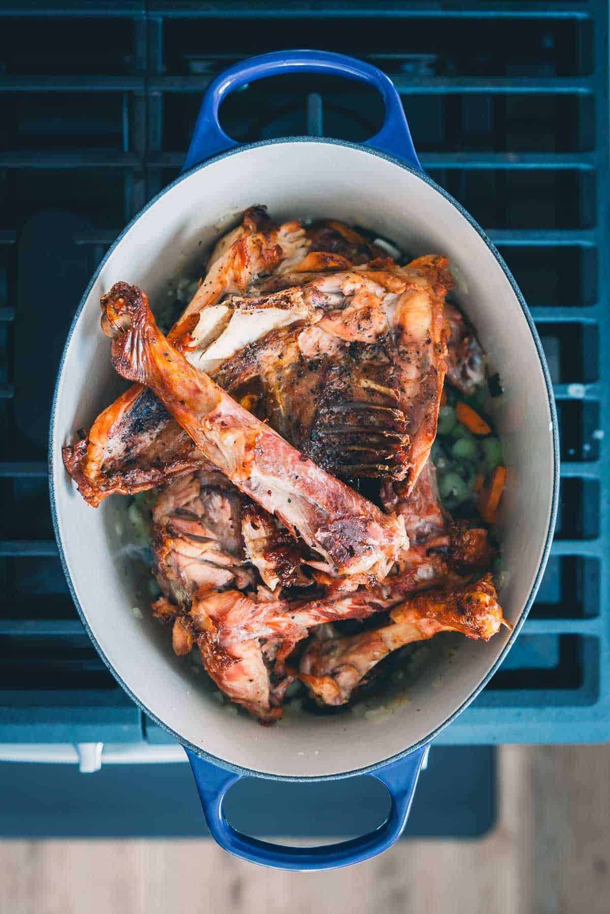 Turkey carcass in a pot on top of a stove.