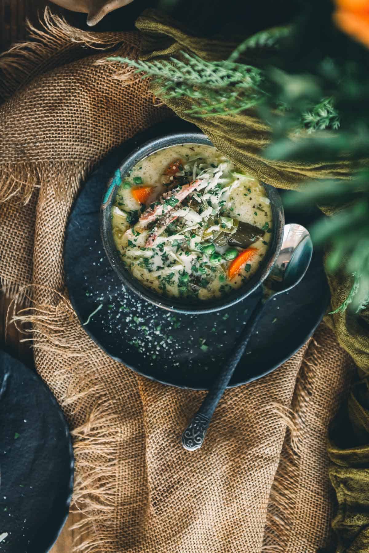 A bowl of turkey soup on a table with flowers.