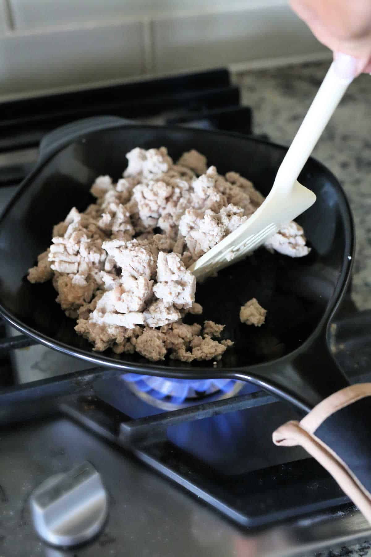Cooked ground turkey on a stove in a nonstick nontoxic ceramic frying pan.