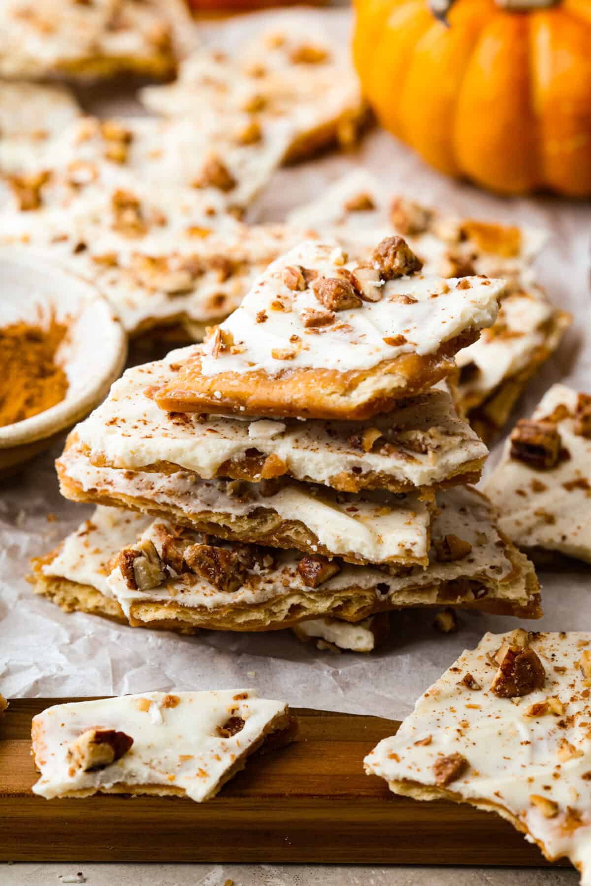Pumpkin spice crack is Christmas crack with a fall twist! Buttery toffee, salty crackers, white chocolate, pumpkin pie spice, and crunchy praline pecans make this an easy treat you won’t be able to stop snacking on. Stack of pumpkin pie spice crack.