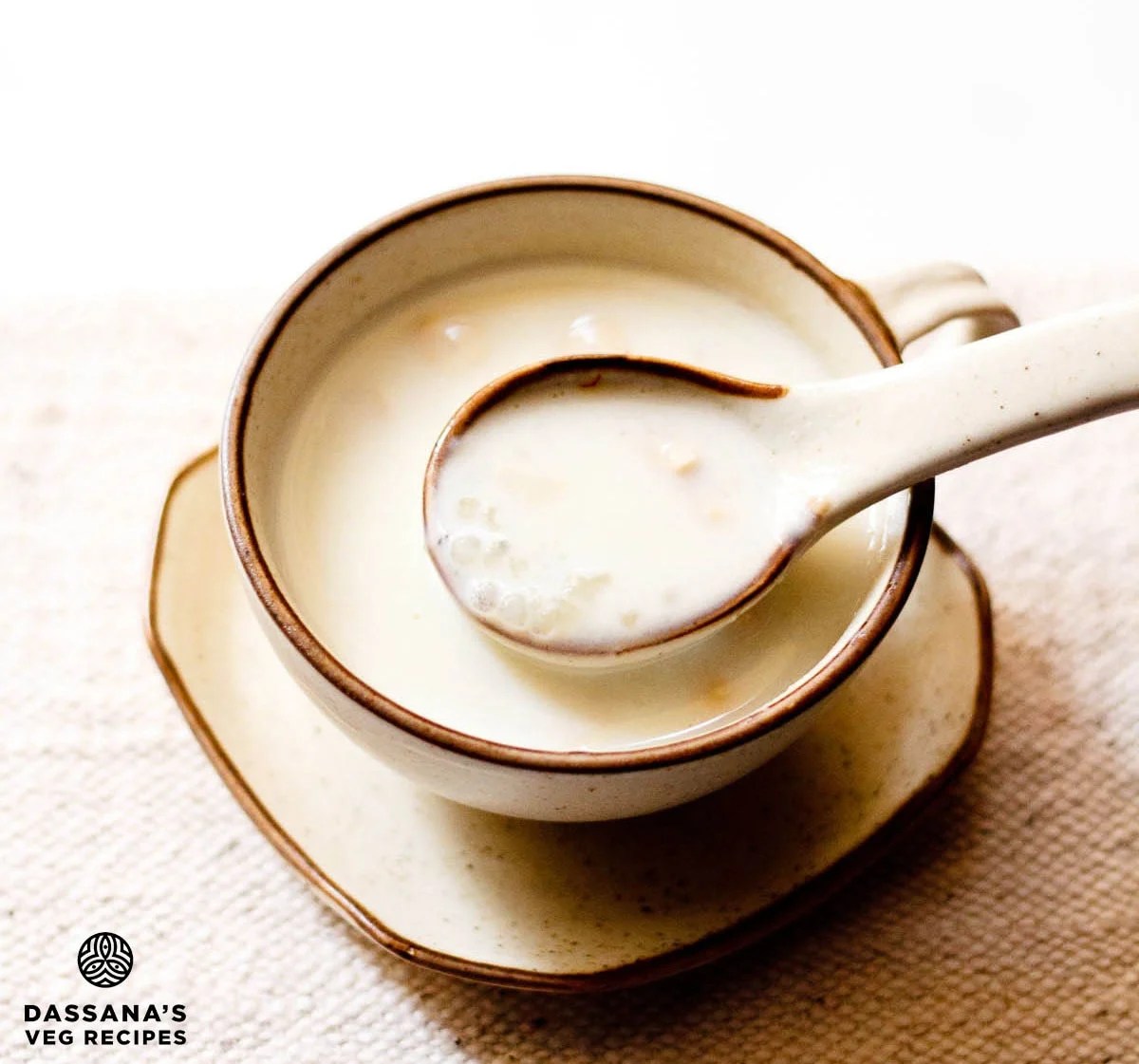 Creamy sabudana kheer in a spoon over a bowl filled with the sago kheer.
