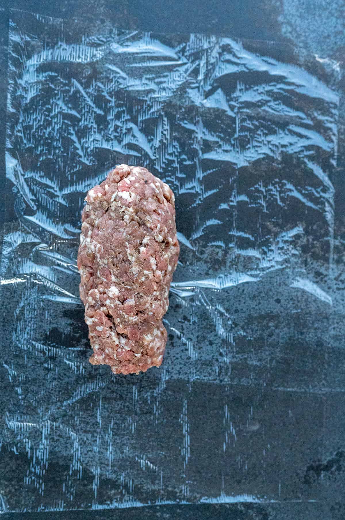 log of sausage on plastic wrap.