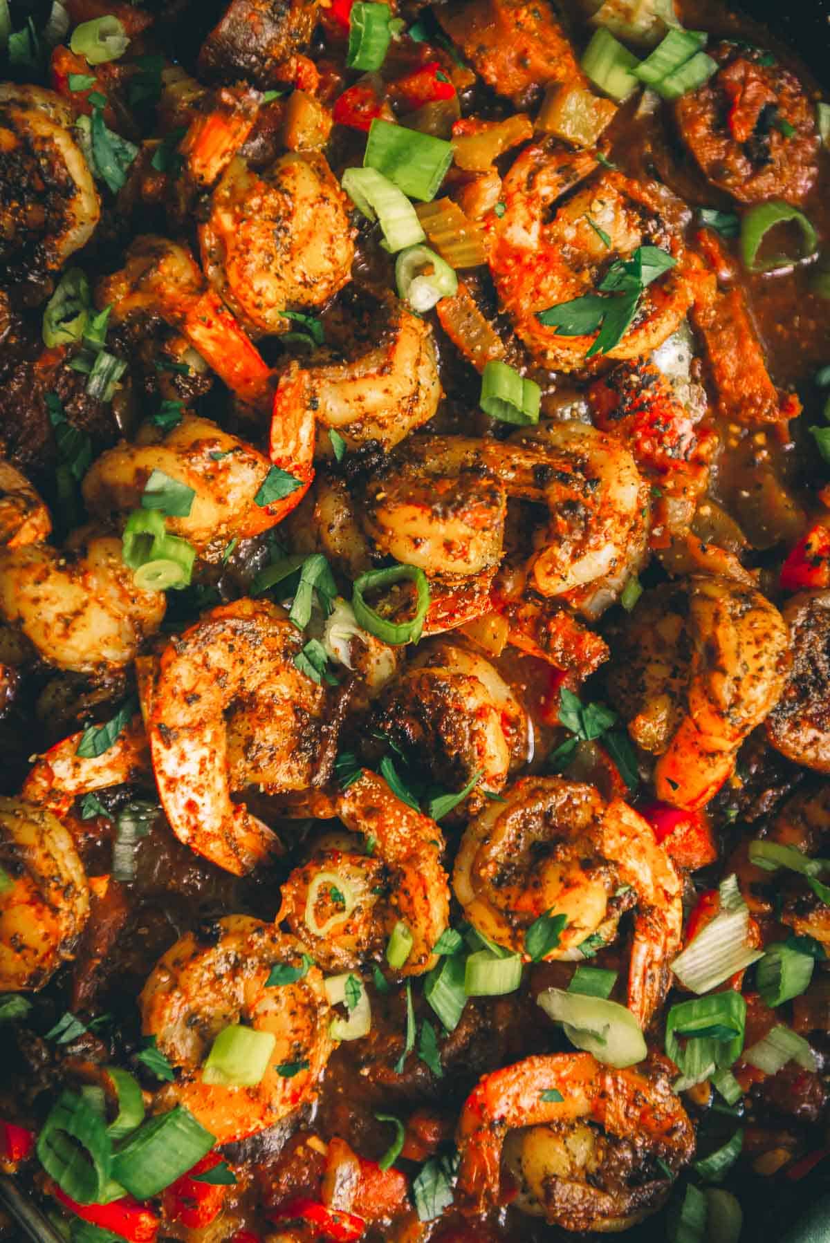 Close up of bright red cooked shrimp in chunky tomato red gravy. 