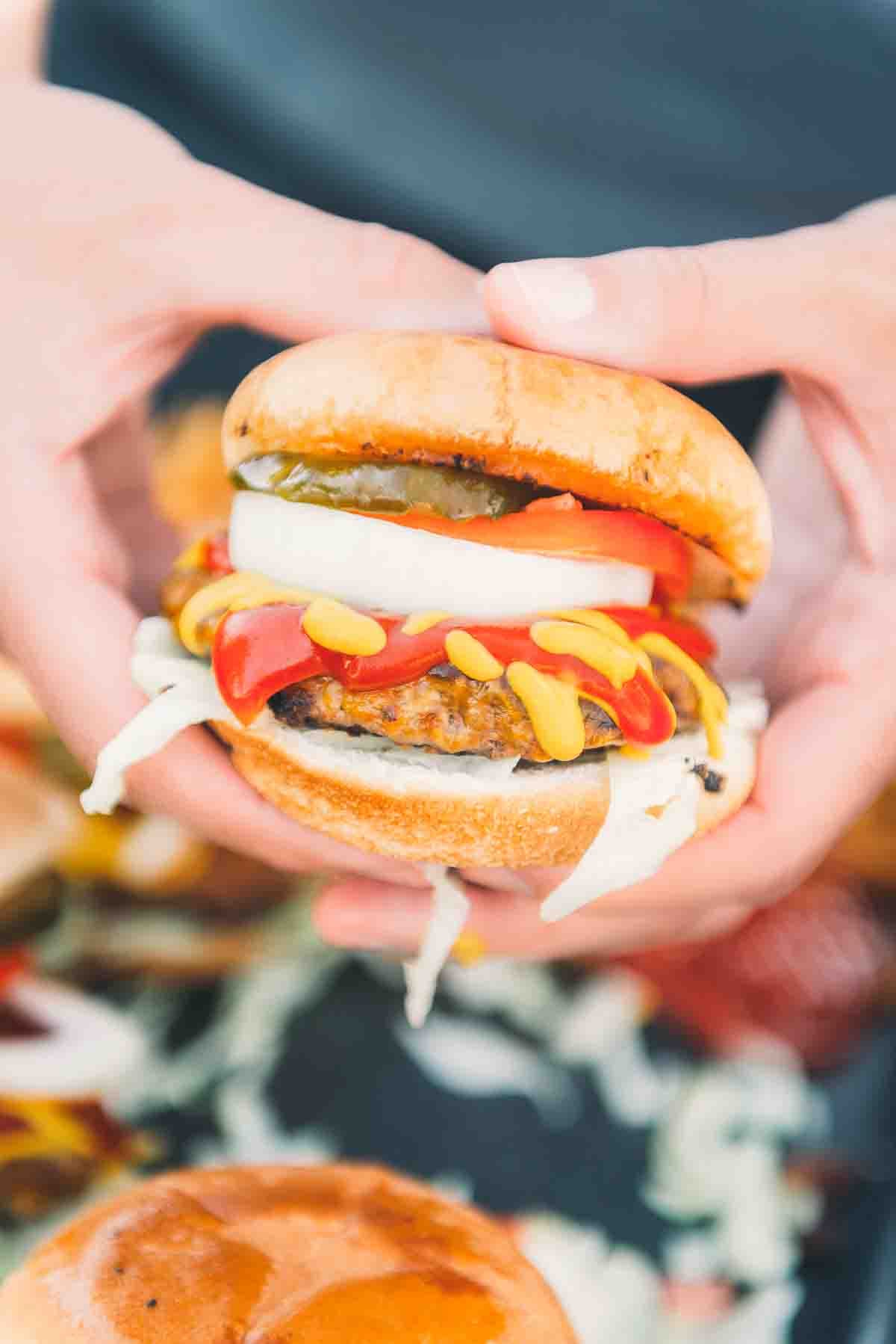 Hands holding a burger.